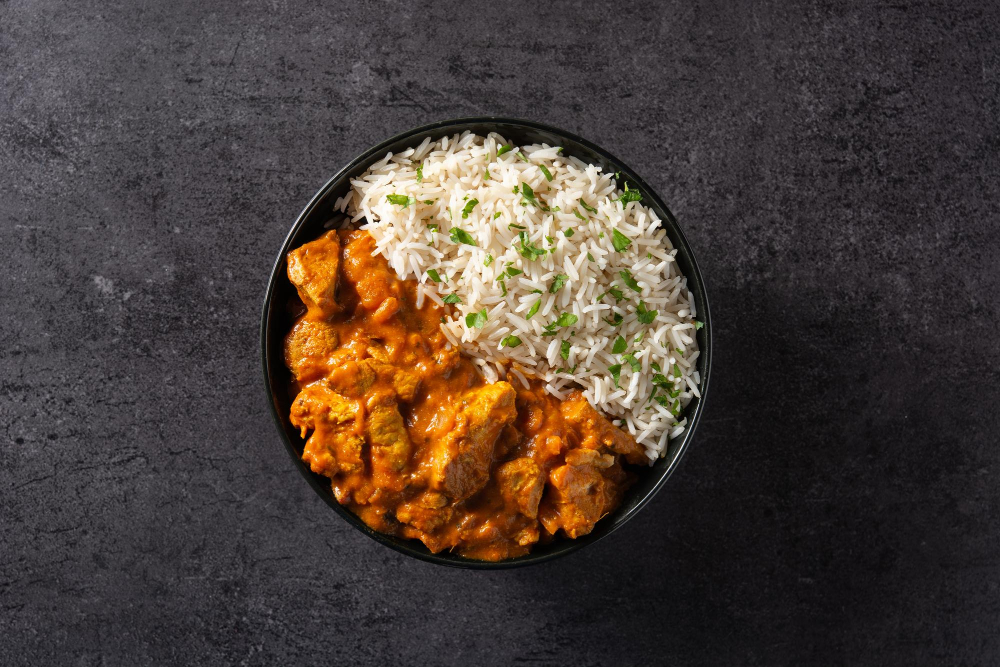 picture of butter chicken in black bowl on black background